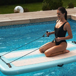 Donna che utilizza una fascia elastica per esercizi su Aquaboard nella piscina